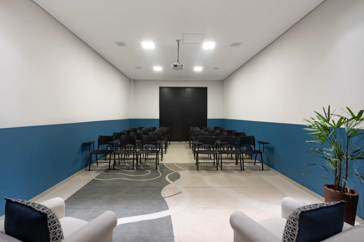 Auditório do LYRATA com cadeiras em fileiras, tapete e projetor