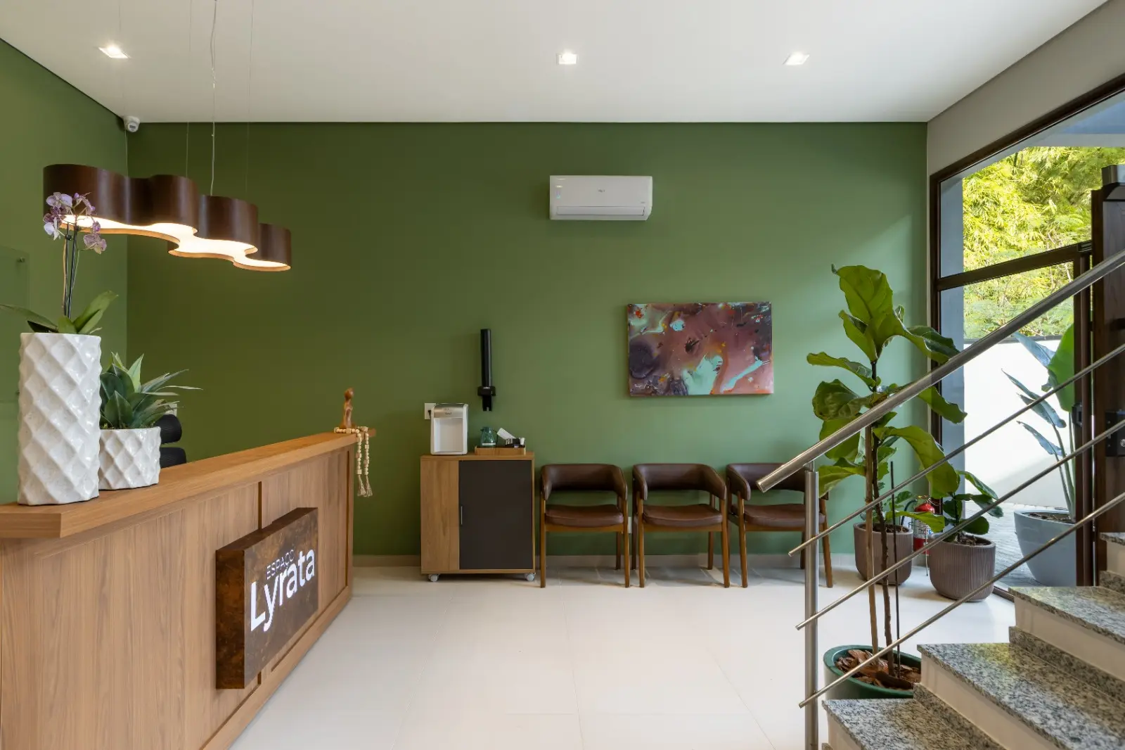 Recepção do LYRATA com balcão de madeira, parede verde e sala de espera